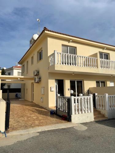 a large yellow house with a white fence at Villa Rhea in Ayia Napa