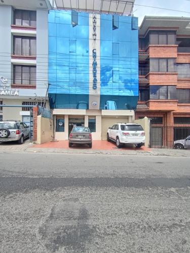 Hostal Chimborazo في Corona: مبنى فيه سيارات تقف امامه