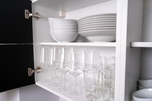 a cupboard with wine glasses and plates in it at NEW Schöne Eigentumswohnung im Zentrum von Deggendorf in Deggendorf