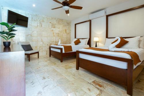 a bedroom with two beds and a flat screen tv at La Aurora Hotel Colonial in Valladolid