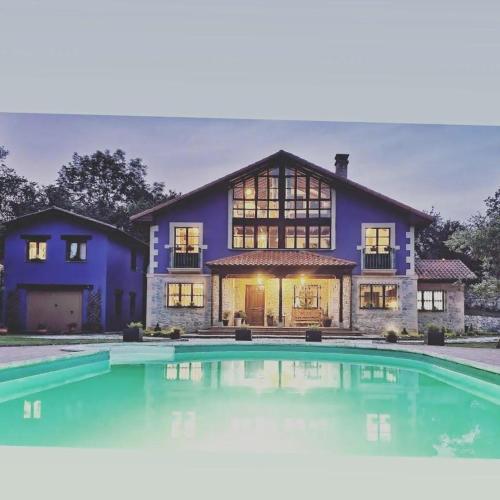 a house with a large swimming pool in front of it at Refugio del Cares in Ortiguero