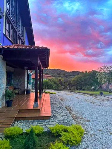 a building with a deck with a sunset in the background at Refugio del Cares in Ortiguero