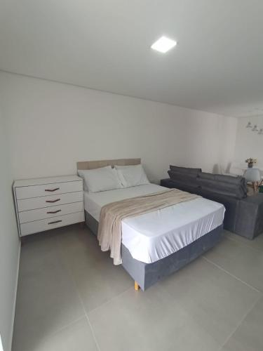 a white bedroom with a bed and a dresser at Studio 23 vista para o mar in Pontal do Paraná
