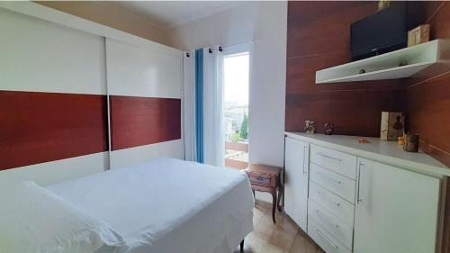 - une chambre avec un lit blanc et une fenêtre dans l'établissement Seu aconchego em Guarulhos, à Guarulhos
