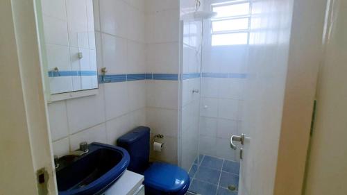 La salle de bains est pourvue d'une douche et de toilettes bleues. dans l'établissement Seu aconchego em Guarulhos, à Guarulhos