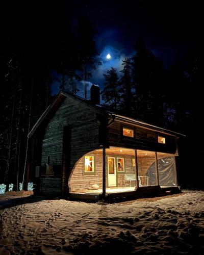 Cabin in the Woods في مالونك: منزل في الليل مع القمر في السماء