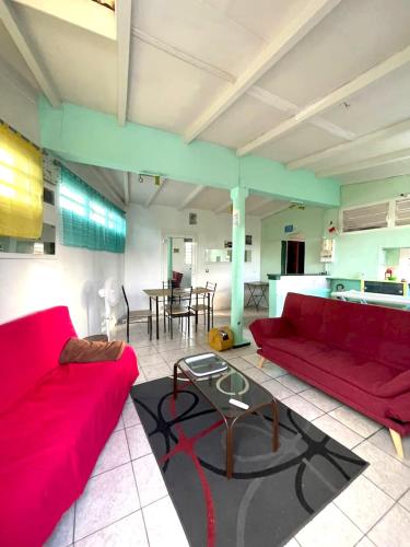 a living room with a red couch and a table at Maison confortable à Baie-Mahault avec climatisation in Baie-Mahault