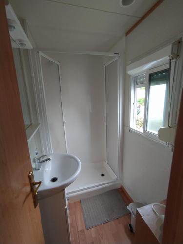 une salle de bain blanche avec un lavabo et une fenêtre dans l'établissement Mobil-Home 54 au Parc Résidentiel de la Plage - 4 personnes, à Gujan-Mestras