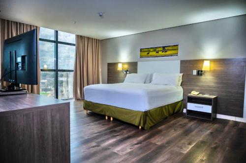 um quarto de hotel com uma cama grande e uma televisão em Hotel Inter Cuiaba em Cuiabá