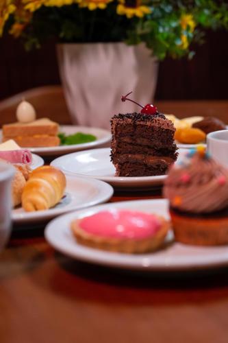 a table with plates of pastries and a piece of cake at Hotel Inter Cuiaba in Cuiabá