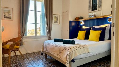 ein Schlafzimmer mit einem großen Bett mit gelben und blauen Kissen in der Unterkunft Casa-Belle Chambres d hotes in Sérignan