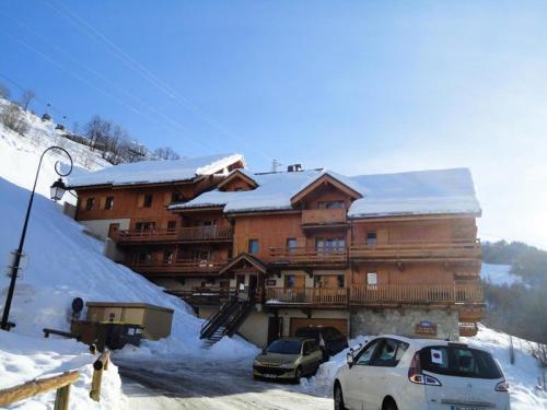 a large wooden building with cars parked in the snow at Résidence Dryades Hameau De La Vallee D'or - 3 Pièces pour 6 Personnes 14 in Valloire