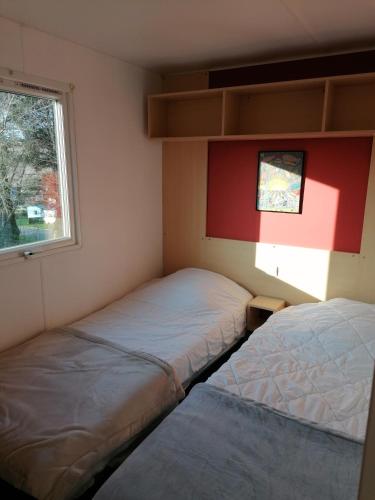 deux lits dans une petite pièce avec une fenêtre dans l'établissement MOBIL HOME 4 personnes en bord de mer - Camping les Goélands, à Saint-Martin-Plage