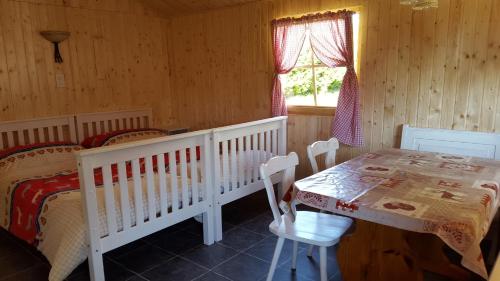 ein Schlafzimmer mit einem Kinderbett, einem Tisch und einem Bett in der Unterkunft SwissCottages Blockhaus in Schönengrund