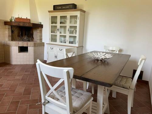cocina con mesa de madera y sillas blancas en Monte Pagliaio, en Terra del Sole