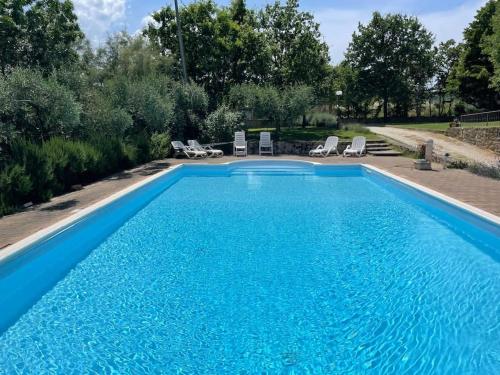 una gran piscina azul con sillas y árboles en Monte Pagliaio, en Terra del Sole