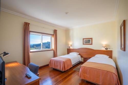 a hotel room with two beds and a window at Hotel Ulveira in Oliveira de Frades