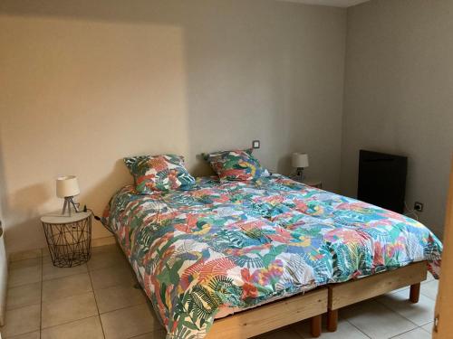ein Bett mit farbenfroher Bettdecke in einem Schlafzimmer in der Unterkunft LE GÎTE DE JEANNOT in La Boisse