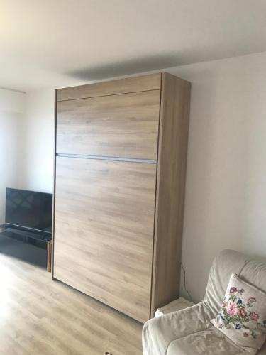une grande armoire en bois dans une chambre avec un canapé dans l'établissement Large studio direct access to the beach, à Pornichet