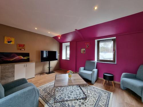 ein Wohnzimmer mit lila Wänden, blauen Stühlen und einem Tisch in der Unterkunft Bella vista in Durbuy
