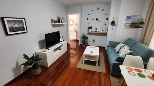 ein Wohnzimmer mit einem blauen Sofa und einem TV in der Unterkunft CasacheloCangas in Cangas