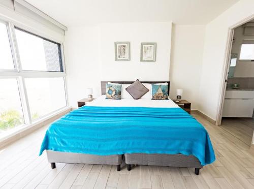 a white bedroom with a large bed with blue sheets at Sanctuary by Playa Caracol Residences in Punta Chame