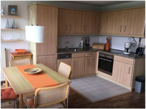 - une cuisine avec des placards en bois, une table, une table et des chaises dans l'établissement Cosy apartment in Garz, à Zudar