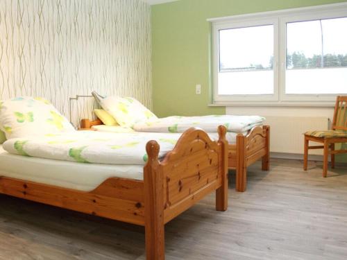 2 letti in legno in una camera con due finestre di Nice apartment in Daun-Waldkönigen 