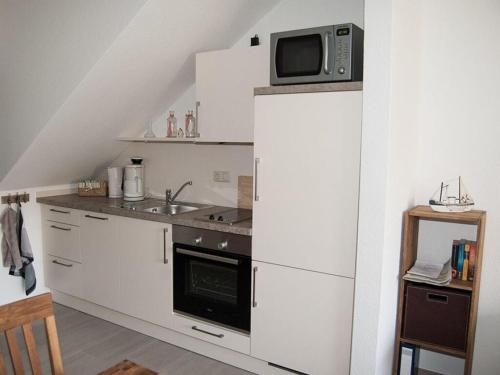 een keuken met een magnetron en een koelkast bij Holiday home Kleiner Friese Dangast in Varel