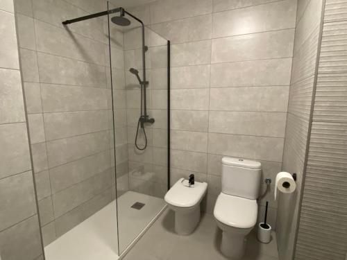 a bathroom with a toilet and a glass shower at Acogedor apartamento en primera línea de playa in Canet de Berenguer