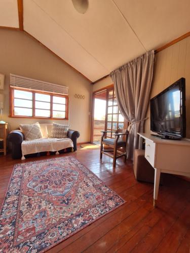 a living room with a couch and a tv at Nyala Bush Cabin in Polokwane