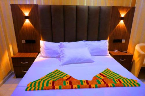 um quarto com uma cama e uma cabeceira em madeira em Texas Royal Hotel em Pokuase