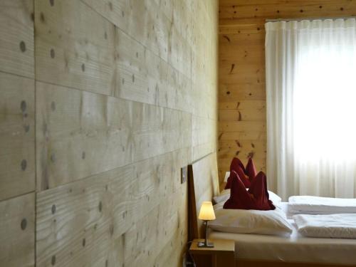 1 dormitorio con pared de madera, cama y ventana en Holiday apartment Rohrhardsberg, en Elzach