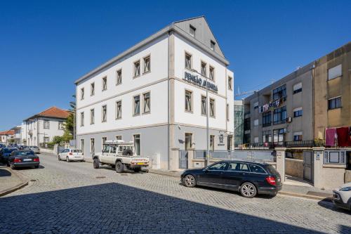 a white building with cars parked in front of it at B&B Pensão Avenida in Oliveira de Frades