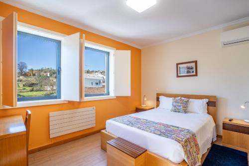 a bedroom with a bed and two windows at B&B Pensão Avenida in Oliveira de Frades