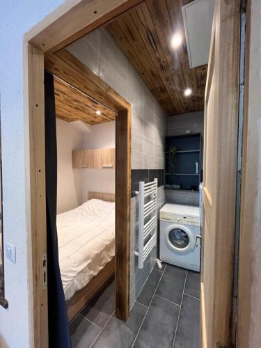 - une petite chambre avec un lit et un lave-linge dans l'établissement Petit appartement à Sevrier, à Sévrier