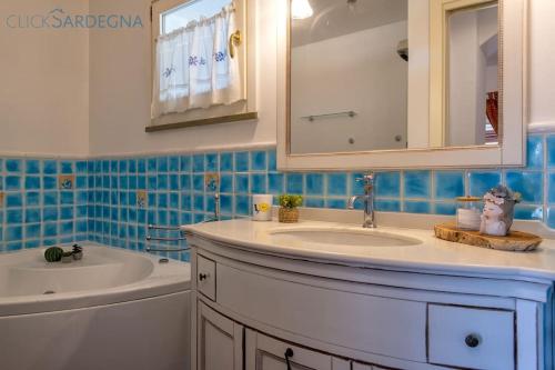 a bathroom with a sink and a mirror and a tub at Alghero Villa Rujia with garden and pool in Porto Conte