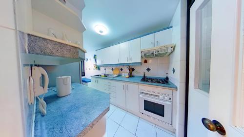 a kitchen with white cabinets and blue counter tops at Altos de San Alfonso in Algarrobo