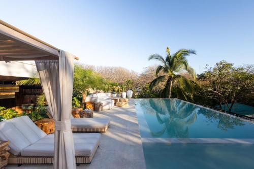 uma piscina com mobiliário branco ao lado de uma casa em Silvestre Nosara Hotel & Residences em Nosara