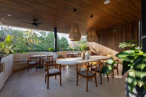 un restaurante con techos de madera, mesas y sillas en Silvestre Nosara Hotel & Residences en Nosara