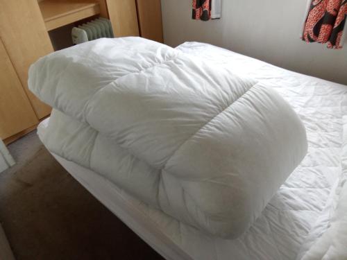 a white blanket on a bed in a bedroom at Arizona Caravan in Camber