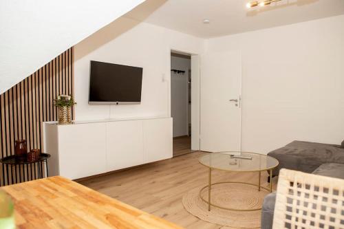 een woonkamer met een televisie aan een witte muur bij DESIGN:Suite am Festspielhaus in Recklinghausen