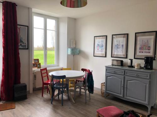 une salle à manger avec une table et des chaises et une fenêtre dans l'établissement l'appart de la Maison du Hommeel, à Gratot
