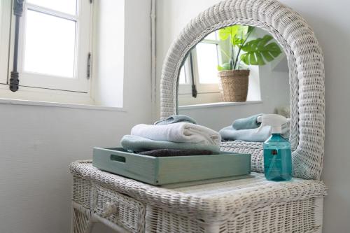a wicker chair with towels and a mirror at Chez Nous Laval in Laval