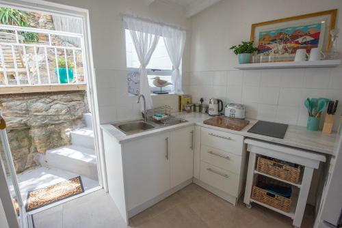Una pequeña cocina con fregadero y encimera. en Beach Haven, en Ciudad del Cabo