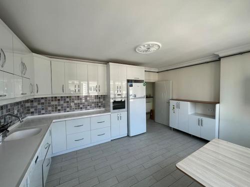 uma grande cozinha com armários brancos e electrodomésticos brancos em 140 m2 Size Ait em Çayirhisar