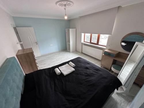 1 dormitorio con 1 cama negra y 2 toallas en My Shelter Balıkesir, en Çayirhisar