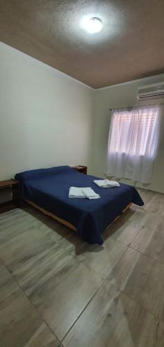 een slaapkamer met een blauw bed en handdoeken bij Depto Catalina in Rafaela