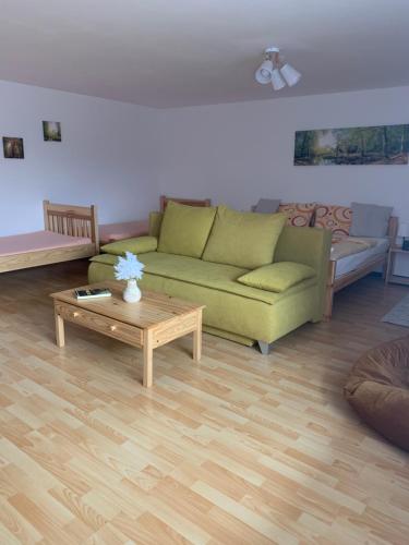 a living room with a green couch and a coffee table at Penzion Pod pecí in Lenora