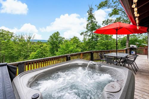 a hot tub on a deck with an umbrella at Modern Cabin w Mountain View Hot Tub & Fire Pit in Morton Grove
